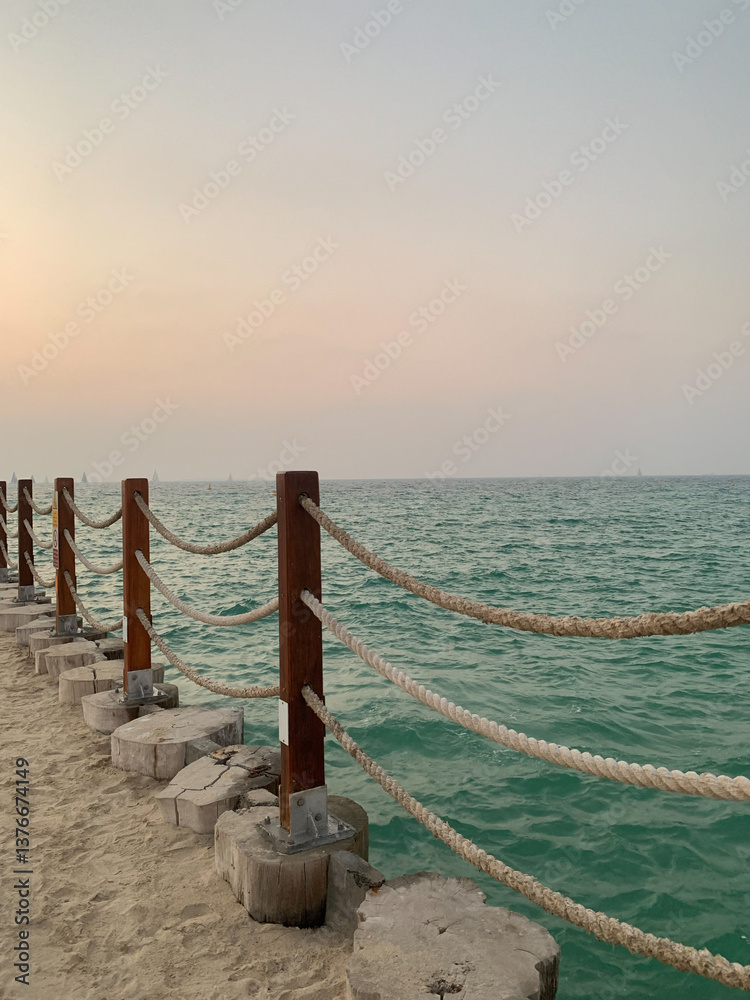 Obraz premium part of the pier with rope fencing at sunset