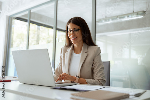 Smiling middle aged business woman using laptop at work in office. Professional female executive entrepreneur in suit working on computer pc at company workplace, doing financial analyze. Copy space
