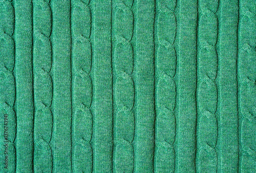 Texture of hand-knitted fabric made of vivid green threads, cables knitting stitch pattern