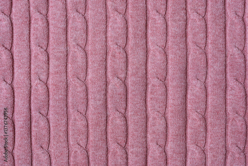 Texture of hand-knitted fabric made of pink threads, cables knitting stitch pattern