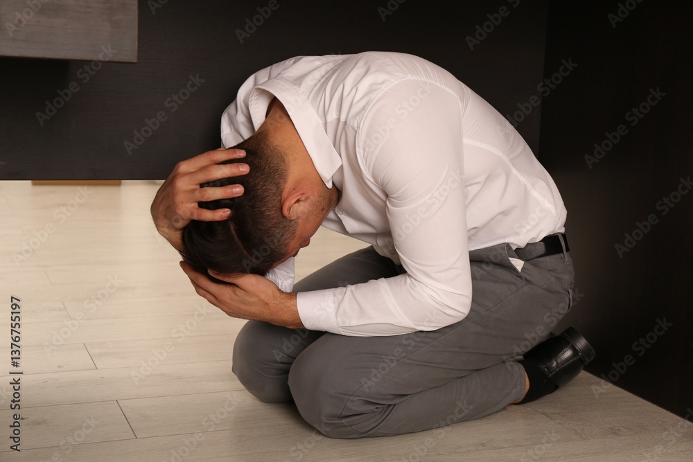 Scared man hiding under office desk during earthquake