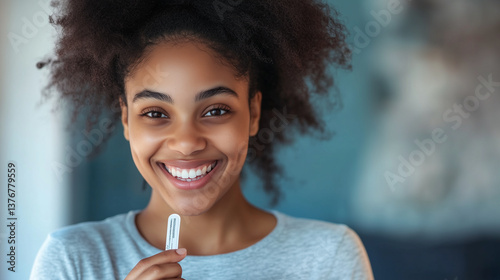 Joyful expectant mother smiling, clutching pregnancy test, celebrating newfound life with emotional anticipation in warm home setting