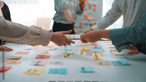 A dynamic creative meeting where team members engage in brainstorming ideas using colorful sticky notes, showcasing collaboration and innovative thinking in an office setting. SACTR