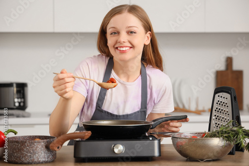 Young woman frying food in ...