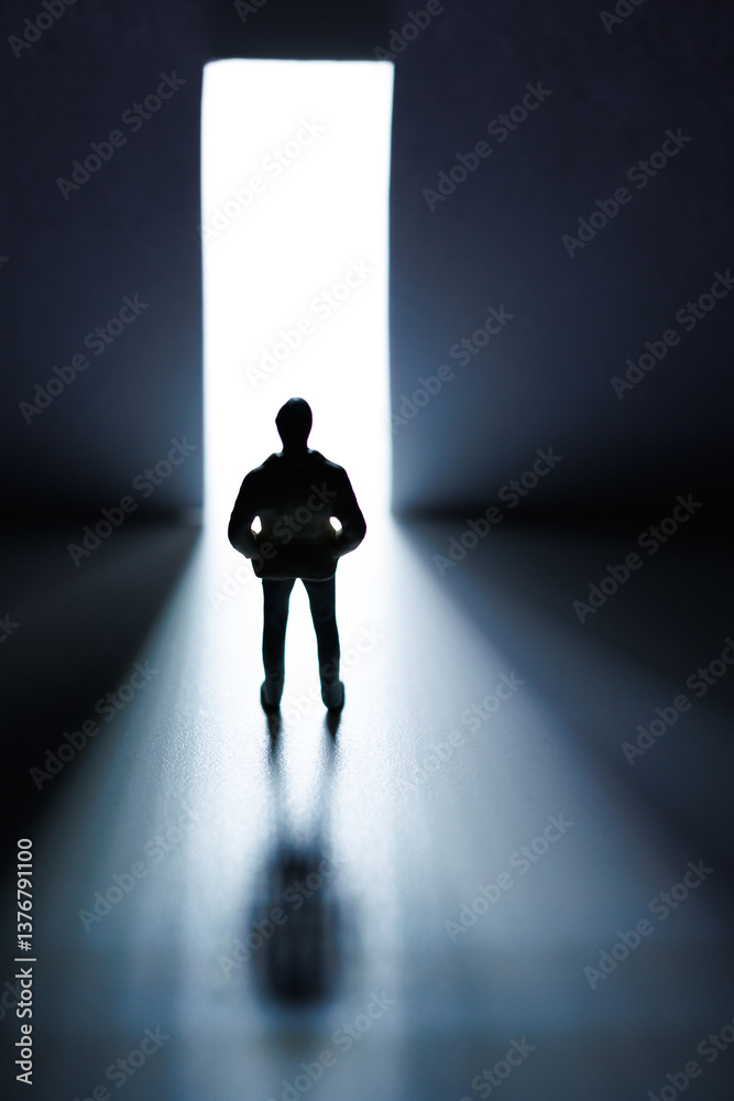 Silhouette of a person standing before a bright light in a dark corridor symbolizing hope and opportunity Silhouette of a person standing before a bright light in a dark corridor symbolizing hope and opportunity