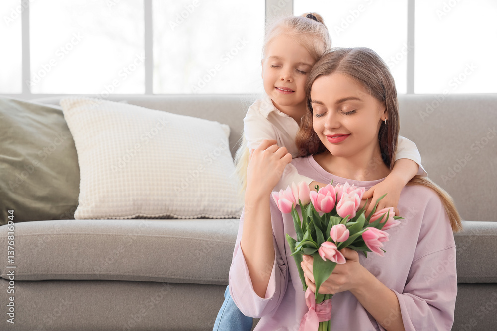 Cute little girl hugging her mom and greeting for Mother's Day with tulips in living room Cute little girl hugging her mom and greeting for Mother's Day with tulips in living room
