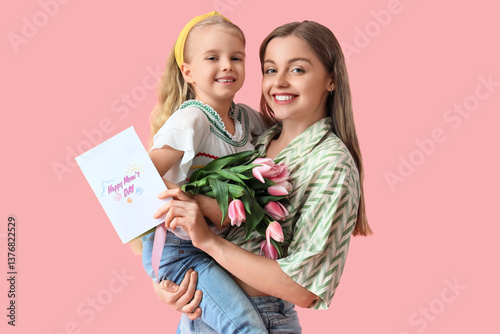 Cute little girl greeting her mom for Mother's Day with tulips and postcard on pink background