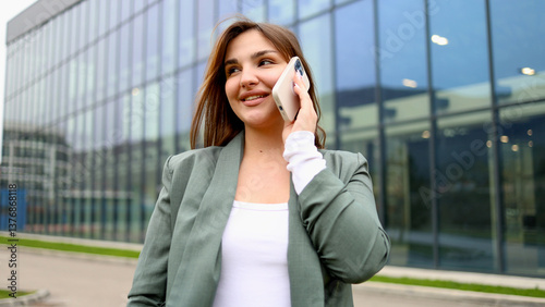 Smiling businesswoman making a phone call outside office building