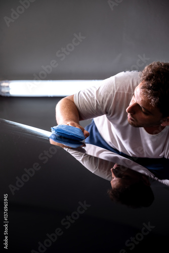 hombre aplicando tratamiento ceramico con paño a mano en automovil