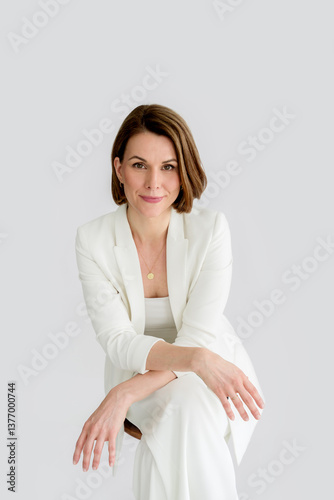 Relaxed portrait of an elegant woman wearing a white suit.