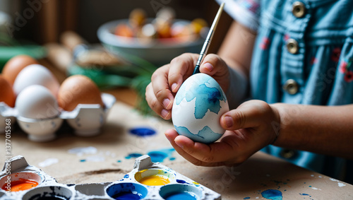 Close-up of a child painting Easter egg with watercolor photo