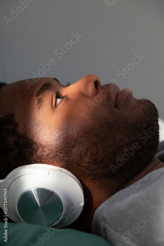Young man relaxing on bed listening to music with headphones
