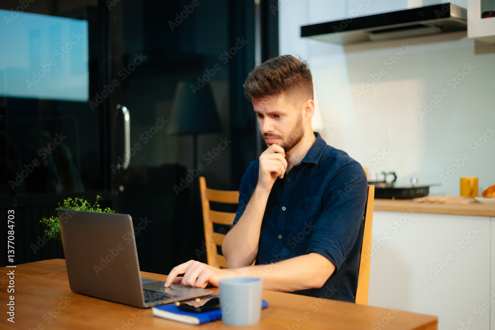 Man using laptop while sitting at home. Young woman sitting in kitchen Man using laptop while sitting at home. Young woman sitting in kitchen