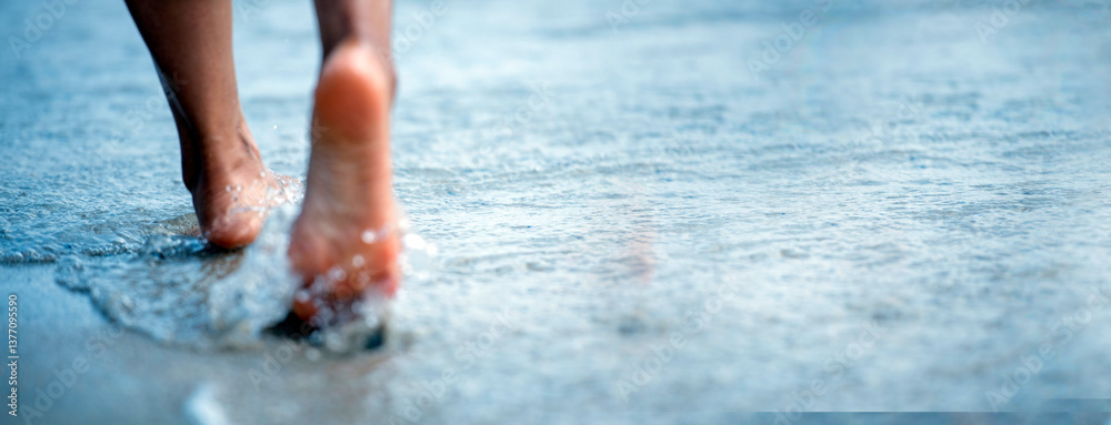 Fototapeta premium Woman bare foot walking on the summer beach. close up leg of young woman walking along wave of sea water and sand on the beach. Enjoyment barefoot walk outdoor with freedom. Relaxation Travel Concept.