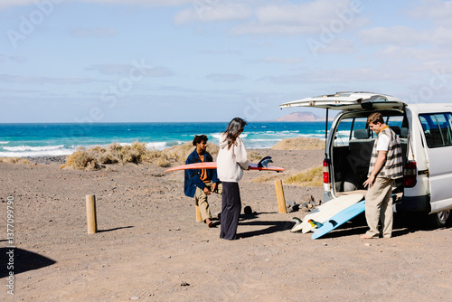 Wide shot with copy space of surfers unloading their surfboards