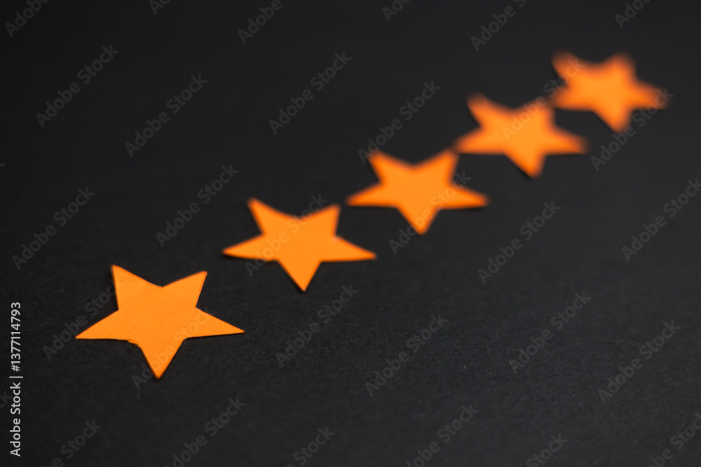 Fototapeta premium Five orange stars in a row representing a good rating and positive feedback.
