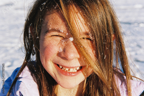 Film portrait of happy child outdoors with snow on her face photo