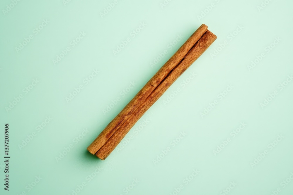 A single cinnamon stick laid diagonally on a green surface A single cinnamon stick laid diagonally on a green surface