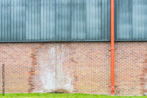 Red drainpipe on an industrial building wall.