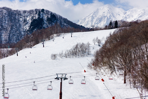 Obraz na płótnie Empty ski chairlift with large, wide slope and mountains behind on a sunny day w salonie