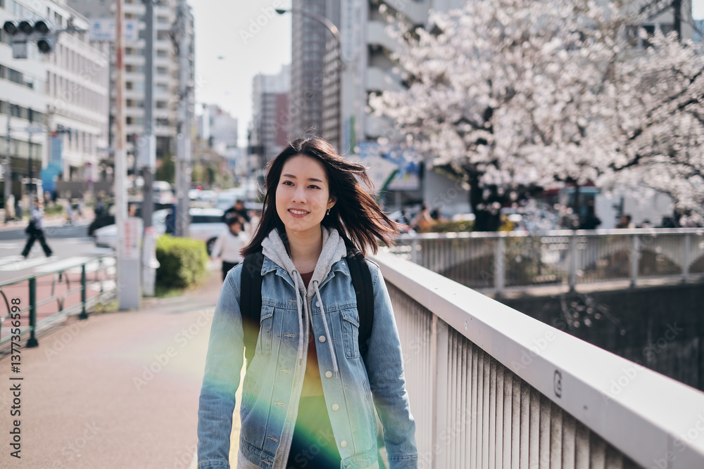 Obraz premium 神田川沿いの桜の街を歩く女性