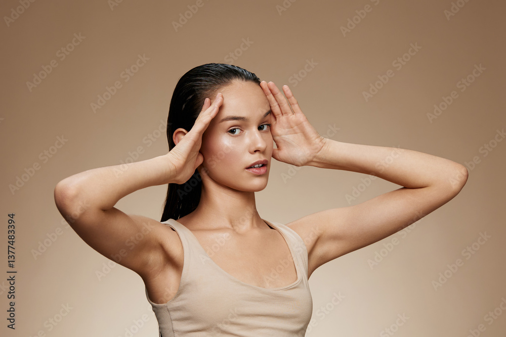 Fototapeta premium Young female model with long hair striking a serene pose against a warm brown background, conveying calmness and mindfulness, ideal for wellness concepts