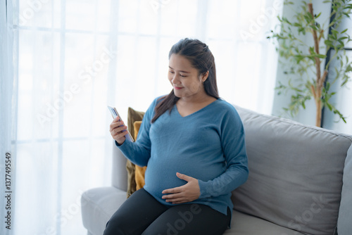 Pregnant asian woman holding smartphone at home using mobile app for pregnant women Positive life moment in pregnancy time Free Download Pregnant asian woman holding smartphone at home using mobile app for pregnant women Positive life moment in pregnancy time - GFXLoad