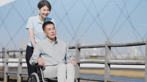 車椅子を押して散策する男性と介護士	

