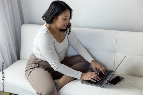 Female in 30s working on laptop at home photo