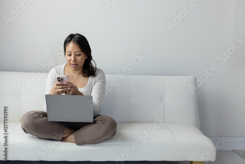 Middle age woman sitting on couch looking at phone photo