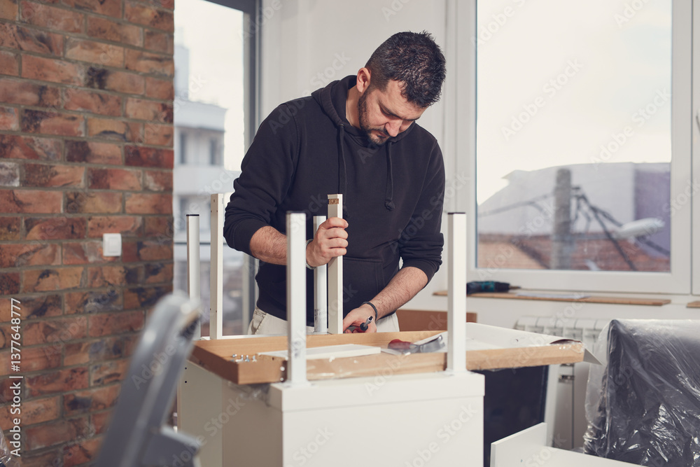 Man working and assembling furniture in a new apartment.