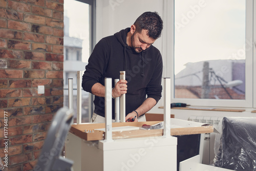 Obraz na płótnie Man working and assembling furniture in a new apartment. w salonie