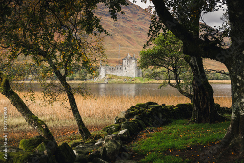 Obraz na płótnie Rolling hills and grazing sheep frame Kilchurn Castle, its ancient ruins reflecting in Loch Awe. A timeless Highland scene bathed in golden Scottish light. w salonie
