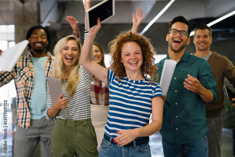 Happy young successful business team celebrating a triumph with arms up in startup office.
