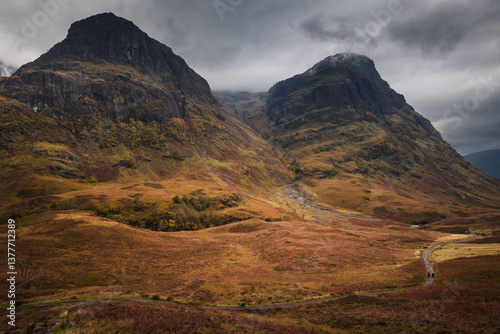 Obraz na płótnie Dramatic peaks and misty valleys define Glen Coe, Scotland’s iconic Highland landscape. Golden light dances on rugged slopes, creating a scene of wild, untamed beauty. w salonie