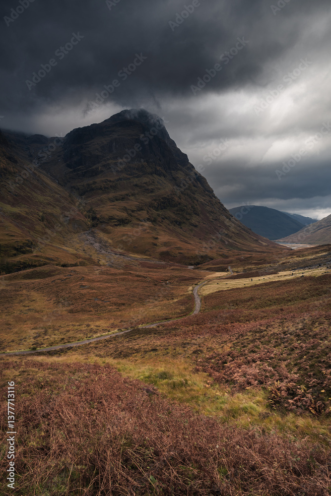 Dramatic peaks and misty valleys define Glen Coe, Scotland’s iconic Highland landscape. Golden light dances on rugged slopes, creating a scene of wild, untamed beauty.
