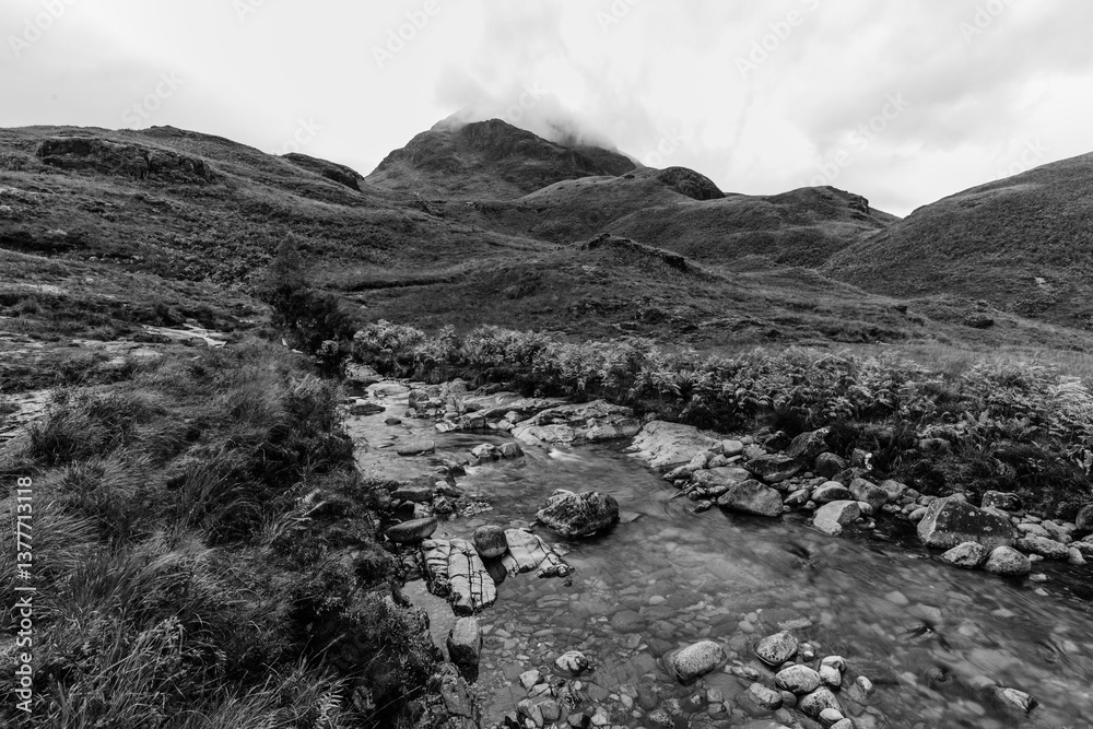 Dramatic peaks and misty valleys define Glen Coe, Scotland’s iconic Highland landscape. Golden light dances on rugged slopes, creating a scene of wild, untamed beauty.