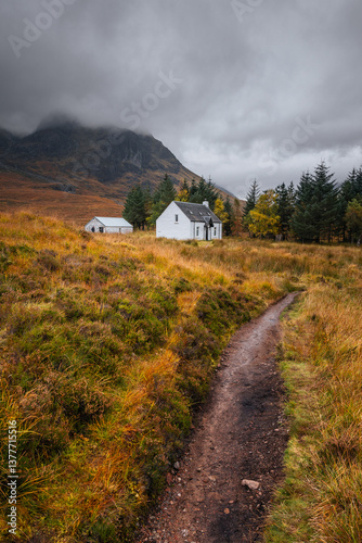 Obraz na płótnie Dramatic peaks and misty valleys define Glen Coe, Scotland’s iconic Highland landscape. Golden light dances on rugged slopes, creating a scene of wild, untamed beauty. w salonie