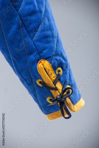 Blue Quilted Sleeve with Yellow Trim and Black Lacing. This image shows a close-up of a blue quilted sleeve with yellow edging and black laces threaded through yellow loops.