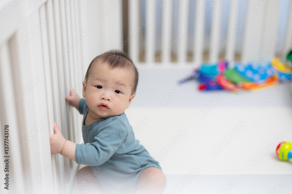 Baby sitting inside crib surrounded by toys