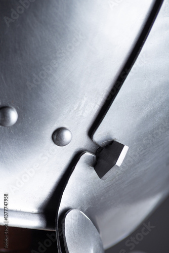 Close-up of Articulated Metal Helmet Visor. Detailed view of the visor mechanism with overlapping plates and rivets.