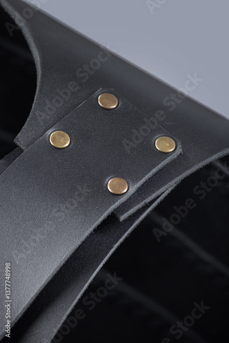 Close-up of Leather Shoulder Straps on Black Cuirass. Detailed view of the black leather armor showing the shoulder straps and brass rivet fastenings.