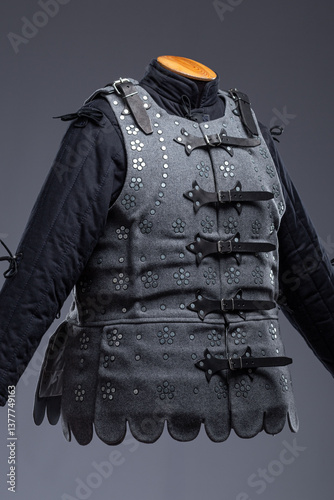 Gray Medieval Brigandine Armor with Leather Straps. This gray brigandine features overlapping metal plates riveted to a fabric base, secured with leather straps.