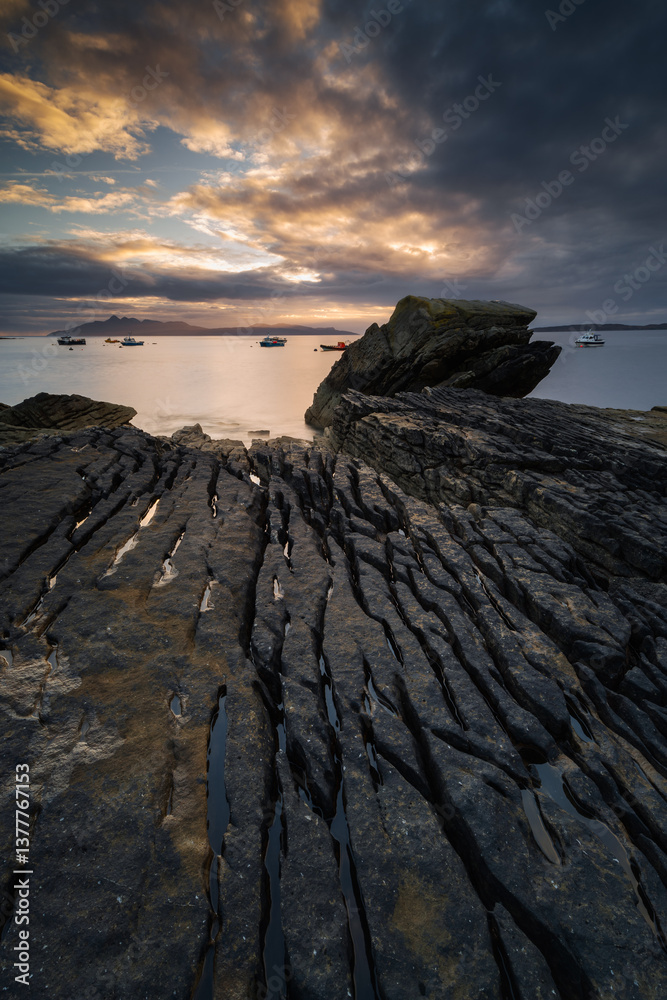 Dramatic waves crash against Elgol’s rugged coast, with the Cuillin Mountains rising in the misty distance. Autumn’s golden light enhances this wild, untamed beauty.