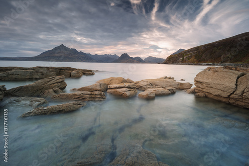 Obraz na płótnie Dramatic waves crash against Elgol’s rugged coast, with the Cuillin Mountains rising in the misty distance. Autumn’s golden light enhances this wild, untamed beauty. w salonie