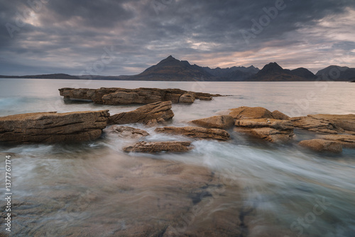 Obraz na płótnie Dramatic waves crash against Elgol’s rugged coast, with the Cuillin Mountains rising in the misty distance. Autumn’s golden light enhances this wild, untamed beauty. w salonie