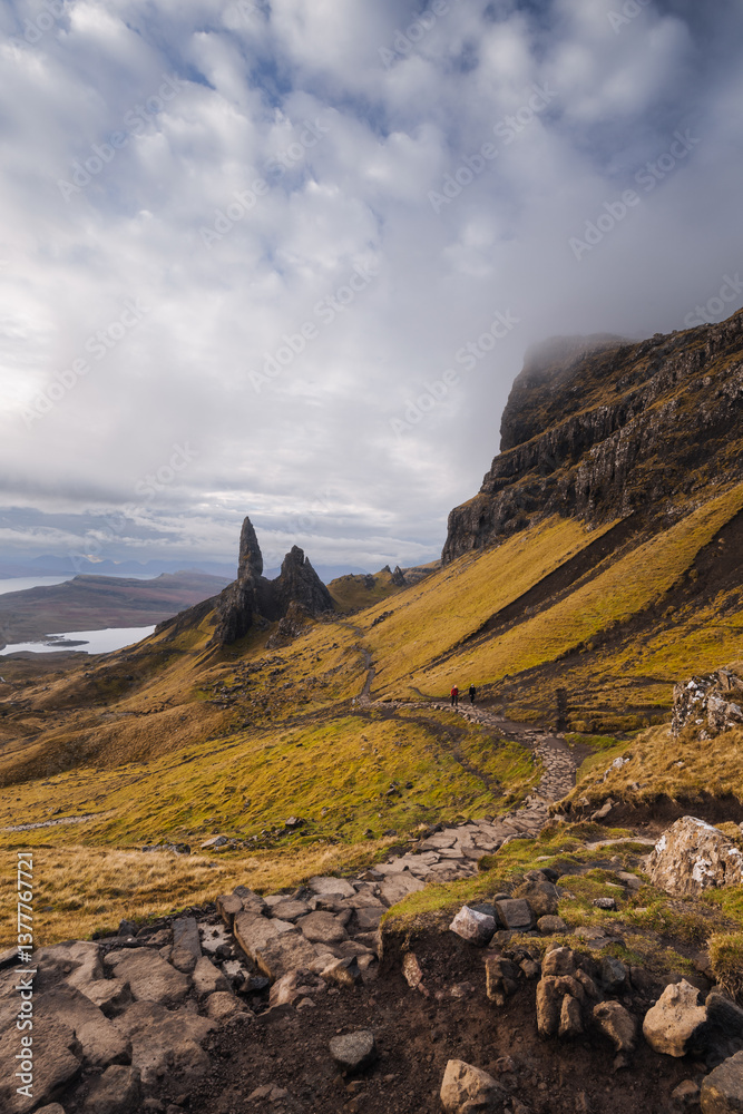 The Old Man of Storr emerges from autumn mist, its towering pinnacles glowing in golden morning light. A mystical, otherworldly Highland scene.