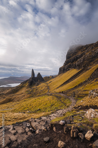 Obraz na płótnie The Old Man of Storr emerges from autumn mist, its towering pinnacles glowing in golden morning light. A mystical, otherworldly Highland scene. w salonie