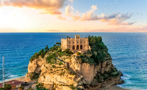 sea landscape of beautiful white temple or castle on a high cliff isle on a rock in crystal clear turquoise sea with waves and beautiful sunset or sunrise on background of seascape