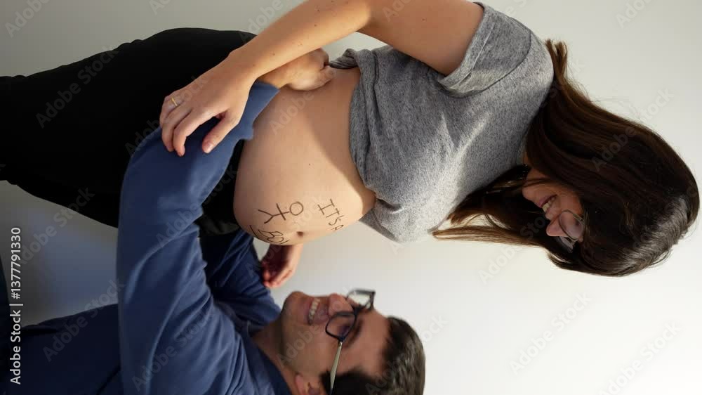 Happy man hugs and kisses his pregnant wife's belly while she smiles ...
